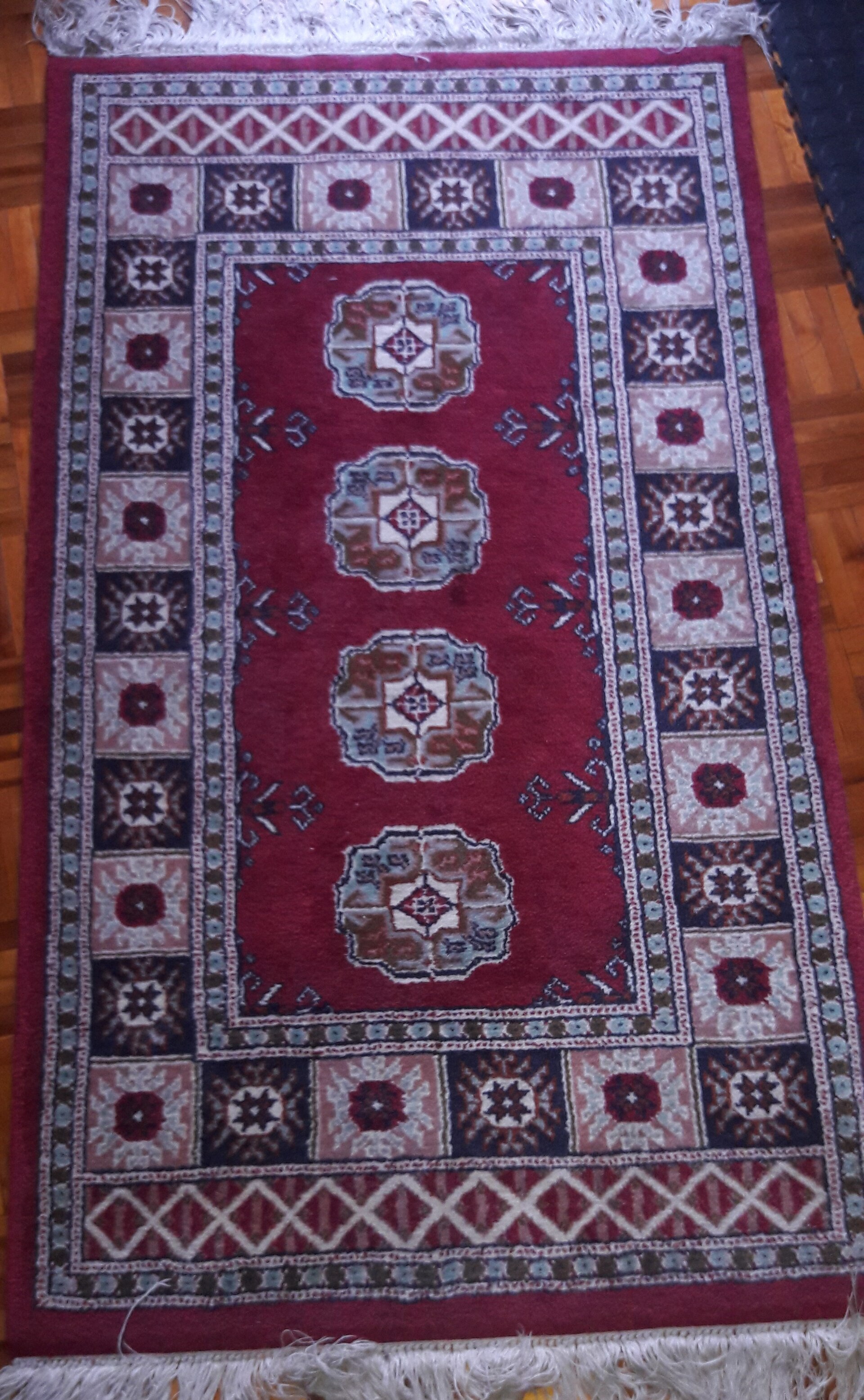 A handwoven rug photographed in flat studio light, deep rust and indigo tones