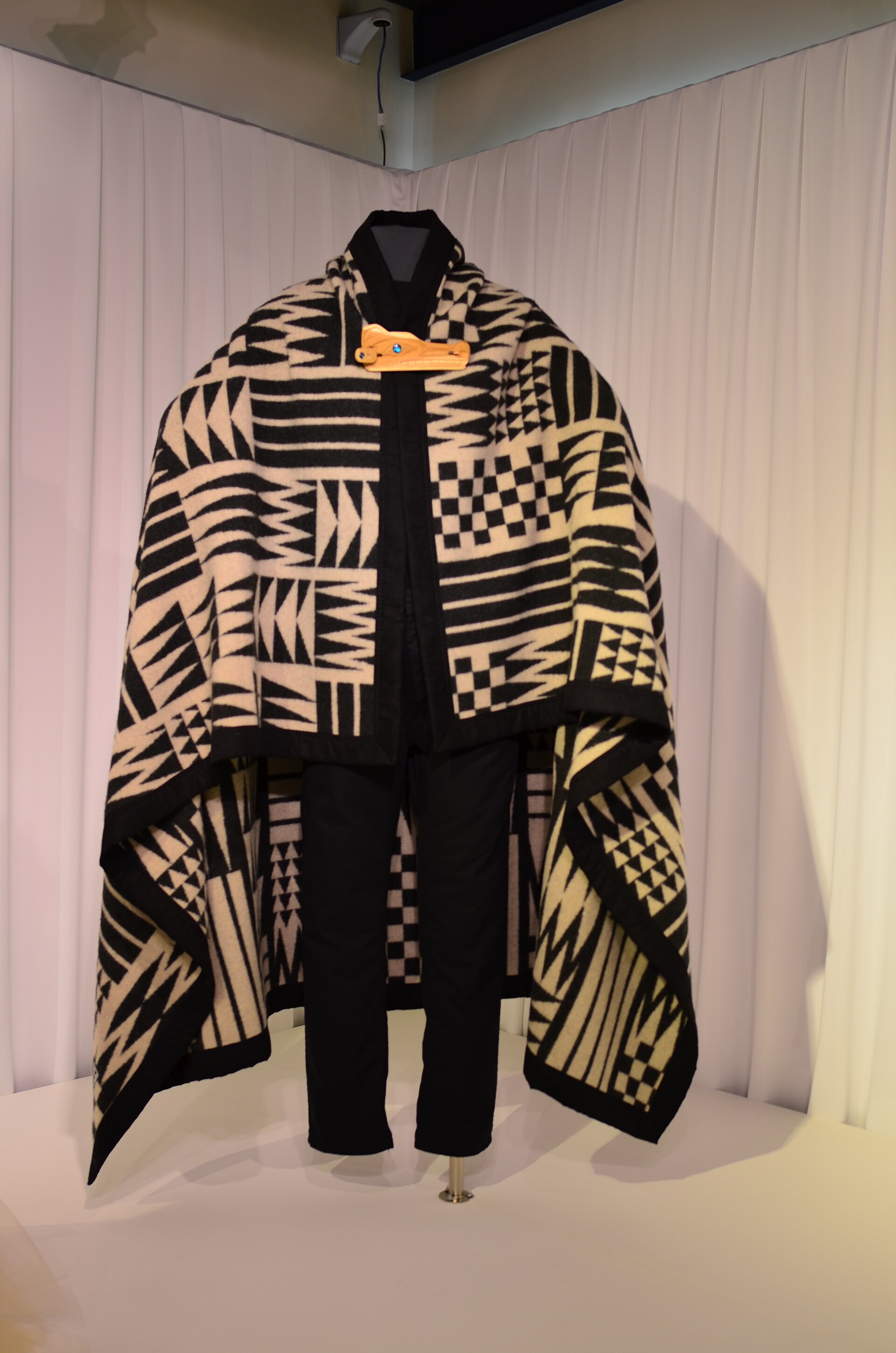 A wool blanket folded to show woven banded pattern in earth and ivory